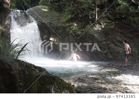 増水した滝つぼで遊ぶ男性 増水した滝つぼで遊ぶ男性 97413165