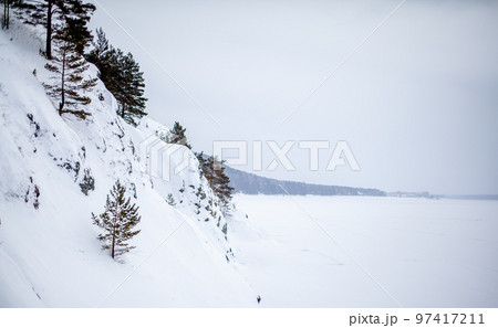 A frozen lake or river in winter. Near the forest and mountains in the snow. Beautiful winter landscapes. Winter trips in nature. 97417211