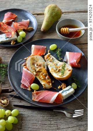 Baked pears stuffed with gorgonzola blue cheese, served with walnuts and South Tyrolean bacon Baked pears stuffed with gorgonzola blue cheese, served with walnuts and South Tyrolean bacon 97420524