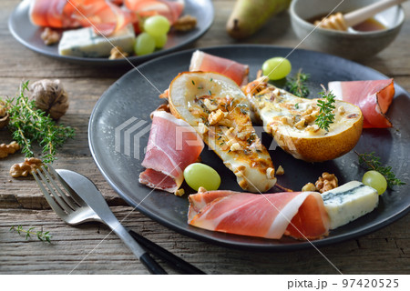 Baked pears stuffed with gorgonzola blue cheese, served with walnuts and South Tyrolean bacon Baked pears stuffed with gorgonzola blue cheese, served with walnuts and South Tyrolean bacon 97420525