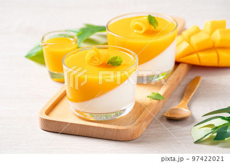 Delicious double colored mango panna cotta mousse pudding on wooden table background. 97422021