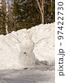 Funny snowman with scarf and hat in winter forest 97422730
