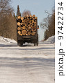rear view of a long heavy industrial cargo ship for transporting timber with a trailer with large pine, spruce, cedar wood, the concept of exporting and shipping wood 97422734