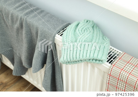 Different winter clothes drying on radiator indoor 97425396