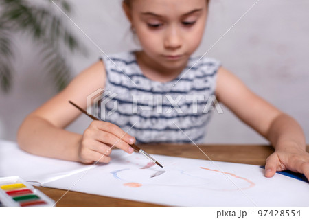 Inspired little girl at the table draw with paints Inspired little girl at the table draw with paints 97428554
