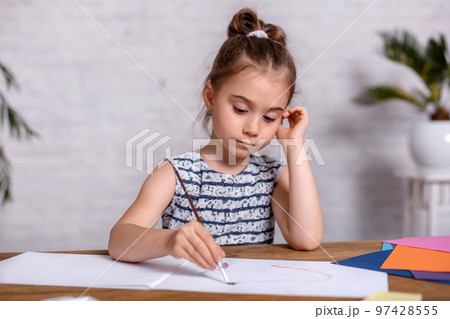 Inspired little girl at the table draw with paints Inspired little girl at the table draw with paints 97428555