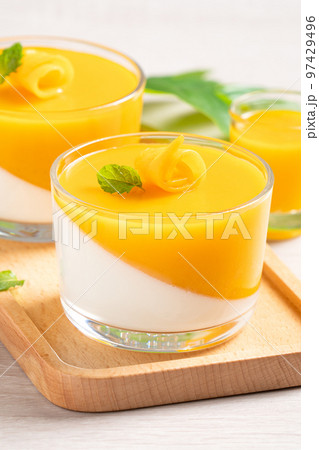 Delicious double colored mango panna cotta mousse pudding on wooden table background. 97429496
