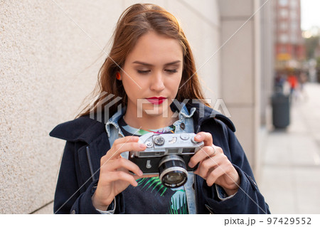 Portrait of a pretty young tourist taking photographs with vintage retro camera Portrait of a pretty young tourist taking photographs with vintage retro camera 97429552
