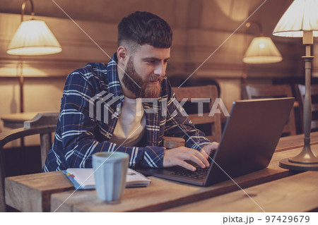 Young professional surfing the Internet on his laptop in a cafe 97429679