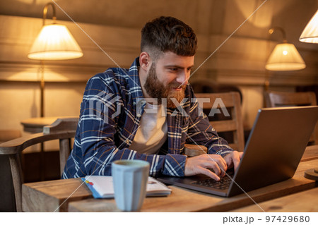 Young professional surfing the Internet on his laptop in a cafe 97429680