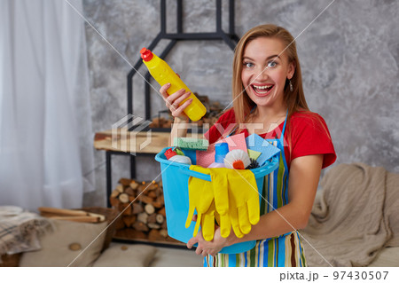 Close-up detergent to cleansing on emotional woman or housewife hands with many household objects in blue bucket in living room. Close-up detergent to cleansing on emotional woman or housewife hands with many household objects in blue bucket in living room. 97430507