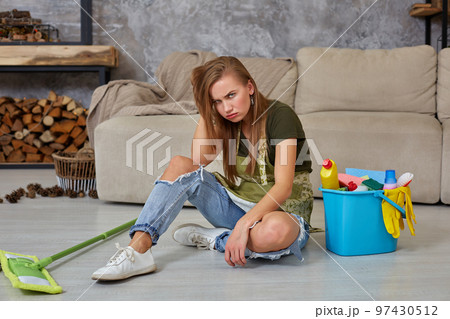 Woman housewife feel tired sitting on floor at living room after cleaning at home. 97430512