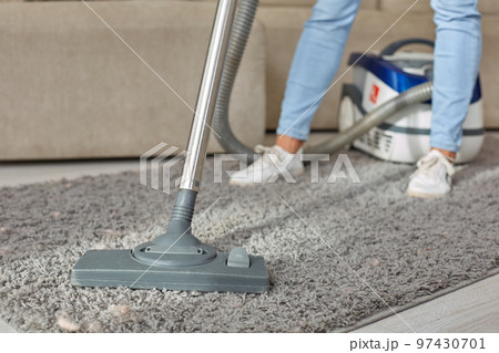 Cropped image of beautiful young woman using a vacuum cleaner while cleaning carpet in the house Cropped image of beautiful young woman using a vacuum cleaner while cleaning carpet in the house 97430701