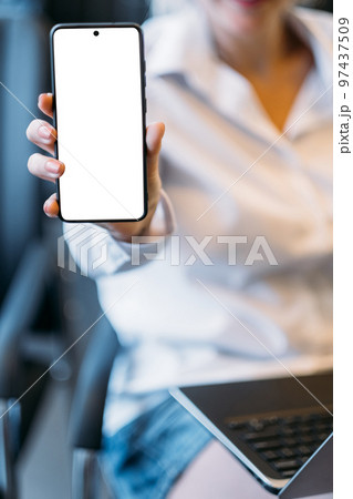 Virtual connection. Mobile mockup. Office place. Unrecognizable woman holding smartphone with blank screen in light room interior. 97437509