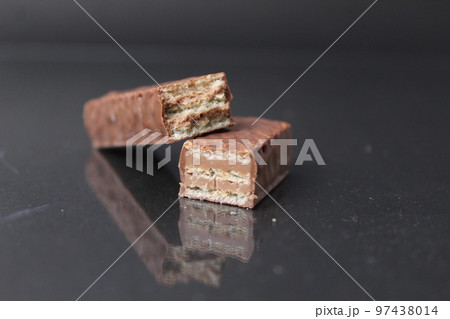 chocolate candy from waffle sheets and chocolate filling praline ganache. Bar cake in chocolate glaze on a black background. Chocolate Sweets Day chocolate candy from waffle sheets and chocolate filling praline ganache. Bar cake in chocolate glaze on a black background. Chocolate Sweets Day 97438014