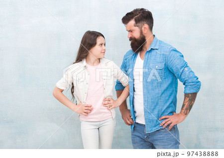 Girl rules. Naughty girl being nasty. Small girl child with father on grey background. Adorable little girl and bearded man putting hands on hips 97438888