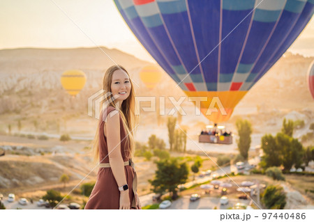 Tourist woman looking at hot air balloons in Cappadocia, Turkey. Happy Travel in Turkey concept. Woman on a mountain top enjoying wonderful view 97440486