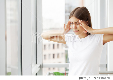 Stressed young office worker holding head because of pain in office Stressed young office worker holding head because of pain in office 97440876
