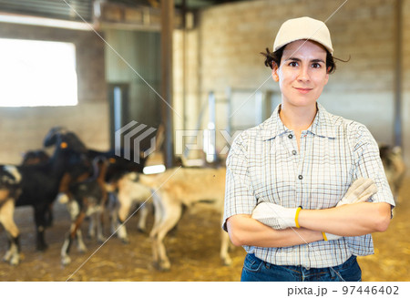 Happy Latin female farmer with crossed hands on chest on goat cattle farm 97446402