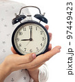 Woman hands holding black alarm clock 97449423
