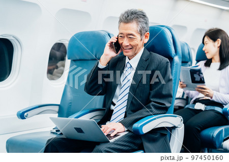 飛行機で出張に出かけるミドルのビジネスマン 飛行機で出張に出かけるミドルのビジネスマン 97450160