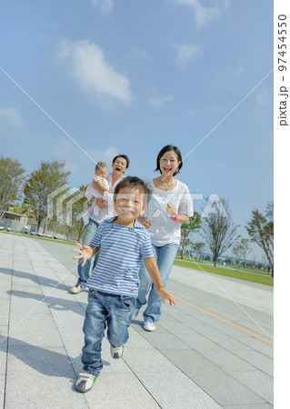 公園の遊歩道で遊ぶ4人家族 97454550