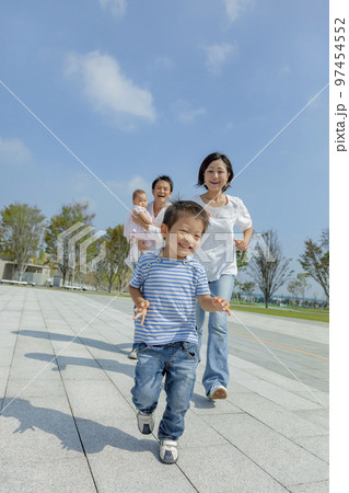 公園の遊歩道で遊ぶ4人家族 97454552