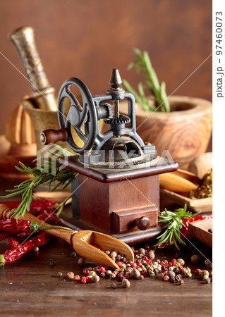 Vintage pepper mill with kitchen utensils, spices and rosemary on a old wooden table. Vintage pepper mill with kitchen utensils, spices and rosemary on a old wooden table. 97460073