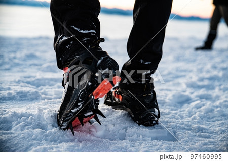Man in crampon spike boots climbs to the top of a snowy mountain in winter. Man in crampon spike boots climbs to the top of a snowy mountain in winter. 97460995