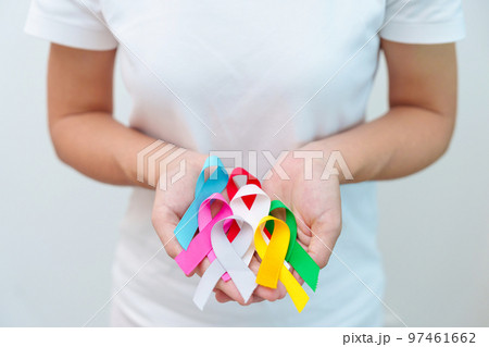 World cancer day, February 4. Hand holding blue, red, green, white, pink, grey and yellow ribbons for supporting people living and illness. Healthcare and Autism awareness day concept 97461662