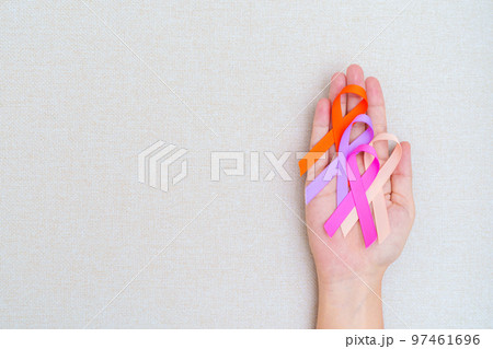 World cancer day, February 4. Hand holding orange, pink, peach and purple ribbons for supporting people living and illness. Healthcare and medical concept 97461696