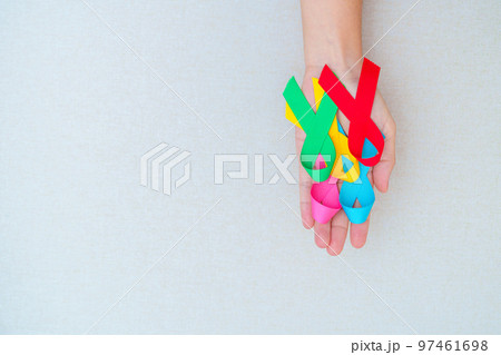 World cancer day, February 4. Hand holding blue, red, green, pink and yellow ribbons for supporting people living and illness. Healthcare and Autism awareness day concept 97461698
