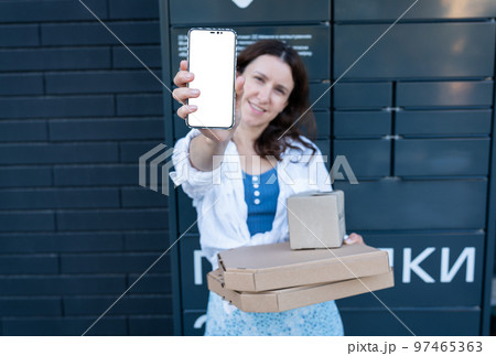 Happy woman holding mobile phone with white screen mockup for inscription and holding many different cardboard boxes with online order, satisfied with fast delivery, buying high quality products. 97465363