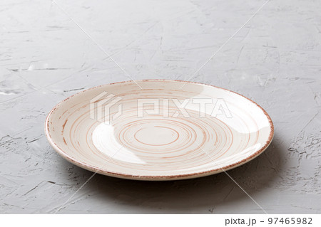 Perspective view of empty light plate on cement background. Empty space for your design Perspective view of empty light plate on cement background. Empty space for your design 97465982