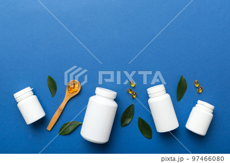 Omega-3 capsules lie in white bottle on a table with green leaves background. Fish oil tablets. Biologically active additives. omega 6, omega 9, vitamin A, E, D, vitamin D3 top view with copy space Omega-3 capsules lie in white bottle on a table with green leaves background. Fish oil tablets. Biologically active additives. omega 6, omega 9, vitamin A, E, D, vitamin D3 top view with copy space 97466080