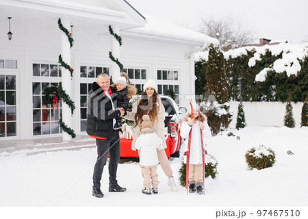 A stylish family with three children is walking in the courtyard of their country house, decorated for Christmas and New Year. Winter walk A stylish family with three children is walking in the courtyard of their country house, decorated for Christmas and New Year. Winter walk 97467510