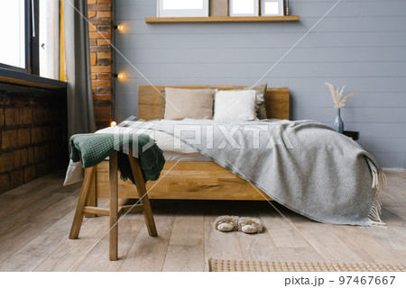 Green blanket on the stool by the bed in the bedroom in the Scandinavian style 97467667