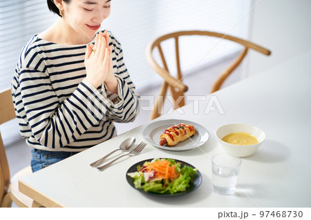 家のダイニングで食事を始める女性 97468730