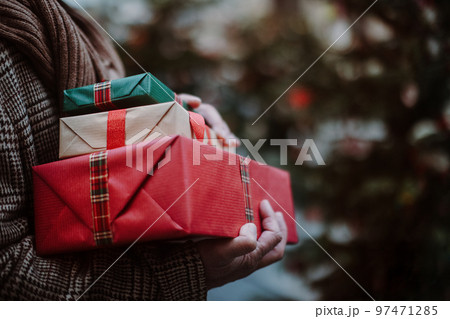 Close-up of man holding gifts, outdoor at Christmas market. Close-up of man holding gifts, outdoor at Christmas market. 97471285