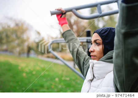 Young muslim woman in sports hijab doing work out in outdoor training ground. Young muslim woman in sports hijab doing work out in outdoor training ground. 97471464
