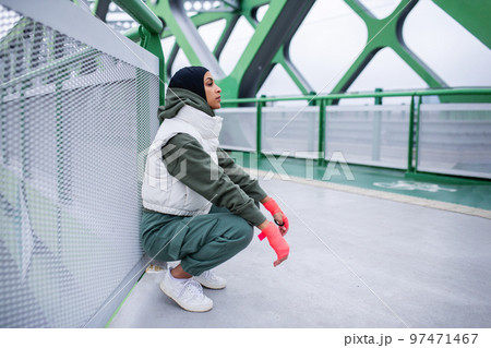Young muslim woman having break during morning jogging. Young muslim woman having break during morning jogging. 97471467