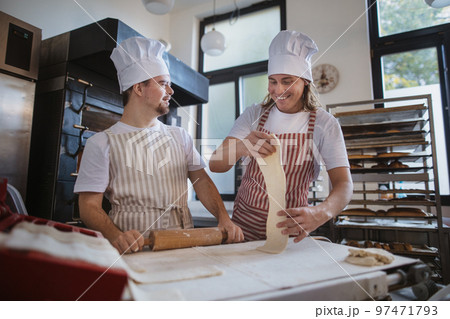 Man with down syndrom helping prepair bread in bakery with his colleague. Concept of integration people with disability into society. 97471793