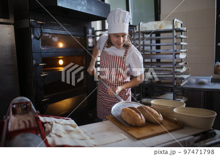 Happy young baker with fresh bread, in bakery. 97471798