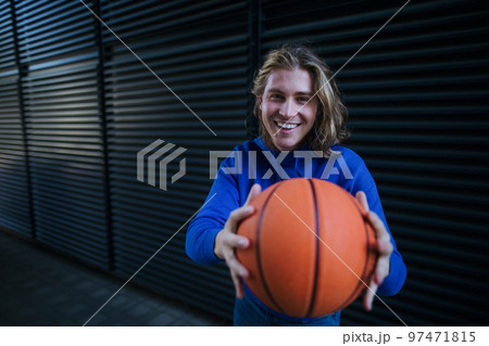 Portrait of young man with cap and sunglasses holding basketball ball,outdoor in city. Youth culture. Portrait of young man with cap and sunglasses holding basketball ball,outdoor in city. Youth culture. 97471815