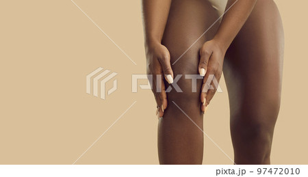 Young black woman suffering from knee pain due to rheumatoid arthritis or leg injury 97472010