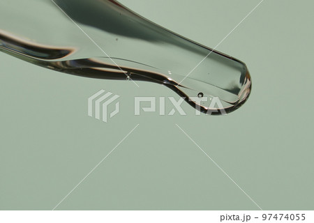 Transparent texture of a drop of serum on a light green background. Transparent sample of cosmetic gel. Hyaluronic acid with space to copy. High quality photo 97474055