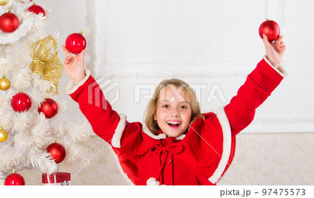 Girl smiling face hold balls ornaments white interior background. Let kid decorate christmas tree. Favorite part decorating. Getting child involved decorating. How to decorate christmas tree with kid 97475573