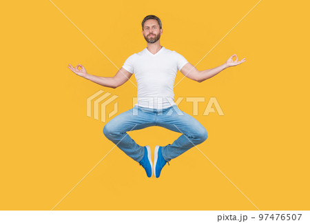 man having levitating meditation isolated on yellow background. meditation guy with mudra gesture. man having levitating meditation isolated on yellow background. meditation guy with mudra gesture. 97476507