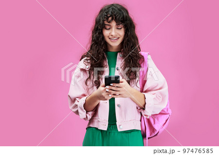 Young modern student in denim jacket looking at screen of mobile phone Young modern student in denim jacket looking at screen of mobile phone 97476585