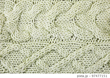 Knitted green background. Large knitted fabric with a pattern. Close-up of a knitted blanket. Horizontal ornament. 97477151